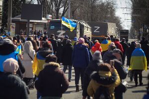 Menschen tragen während einer Kundgebung in Cherson ukrainische Fahnen., © Uncredited/AP/dpa