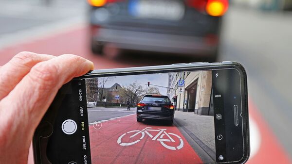 Auf einem Smartphone ist das Bild eines Autos zu sehen, das auf einem Radfahrstreifen hält., © Oliver Berg/dpa/Illustration