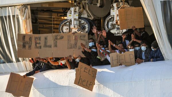 Migranten halten Transparente mit der Bitte um Hilfe an Deck des unter norwegischer Flagge fahrenden Schiffes «Geo Barents»., © Salvatore Cavalli/AP/dpa