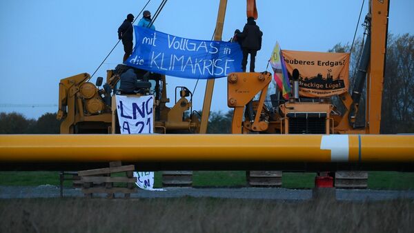 Aktivisten sitzen auf Baufahrzeugen und haben Plakate mit der Aufschrift "mit Vollgas in die Klimakrise" und "Sauberes Erdgas? Eine dreckige Lüge" gespannt., © Jonas Walzberg/dpa