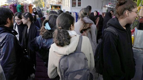 Iranische Frauen gehen ohne ihr vorgeschriebenes islamisches Kopftuch zu tragen durch Teheran., © Vahid Salemi/AP/dpa