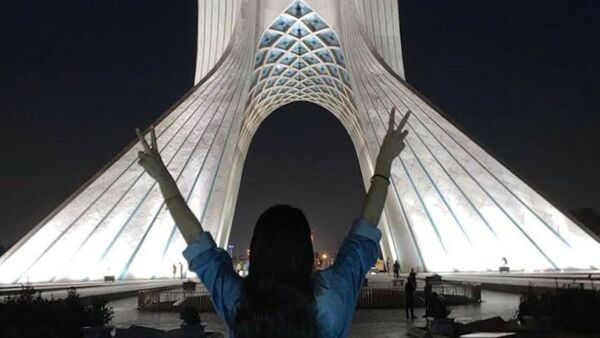 Ein Mädchen steht ohne das vorgeschriebene Kopftuch vor dem Azadi-Turm und zeigt mit beiden Händen das Victory-Zeichen. Bei landesweiten Protesten sind im Iran erneut viele Menschen getötet worden., © Anonymous/ZUMA Press Wire/dpa