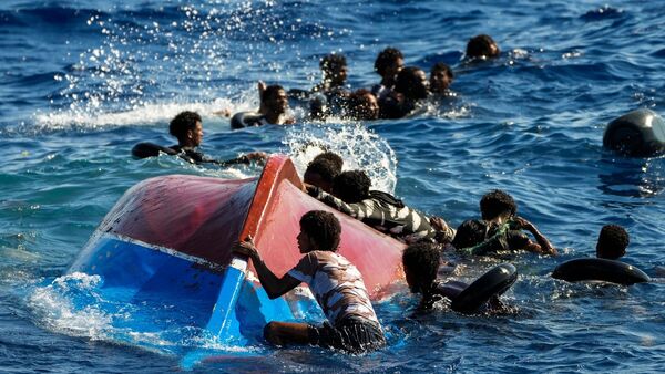 Migranten schwimmen neben ihrem umgestürzten Holzboot im Mittelmeer (Archiv)., © Francisco Seco/AP/dpa